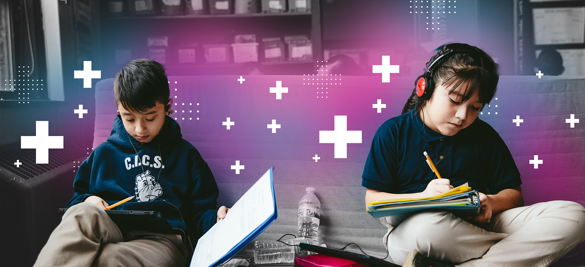 Two students in a classroom working alongside each other wearing headphones.