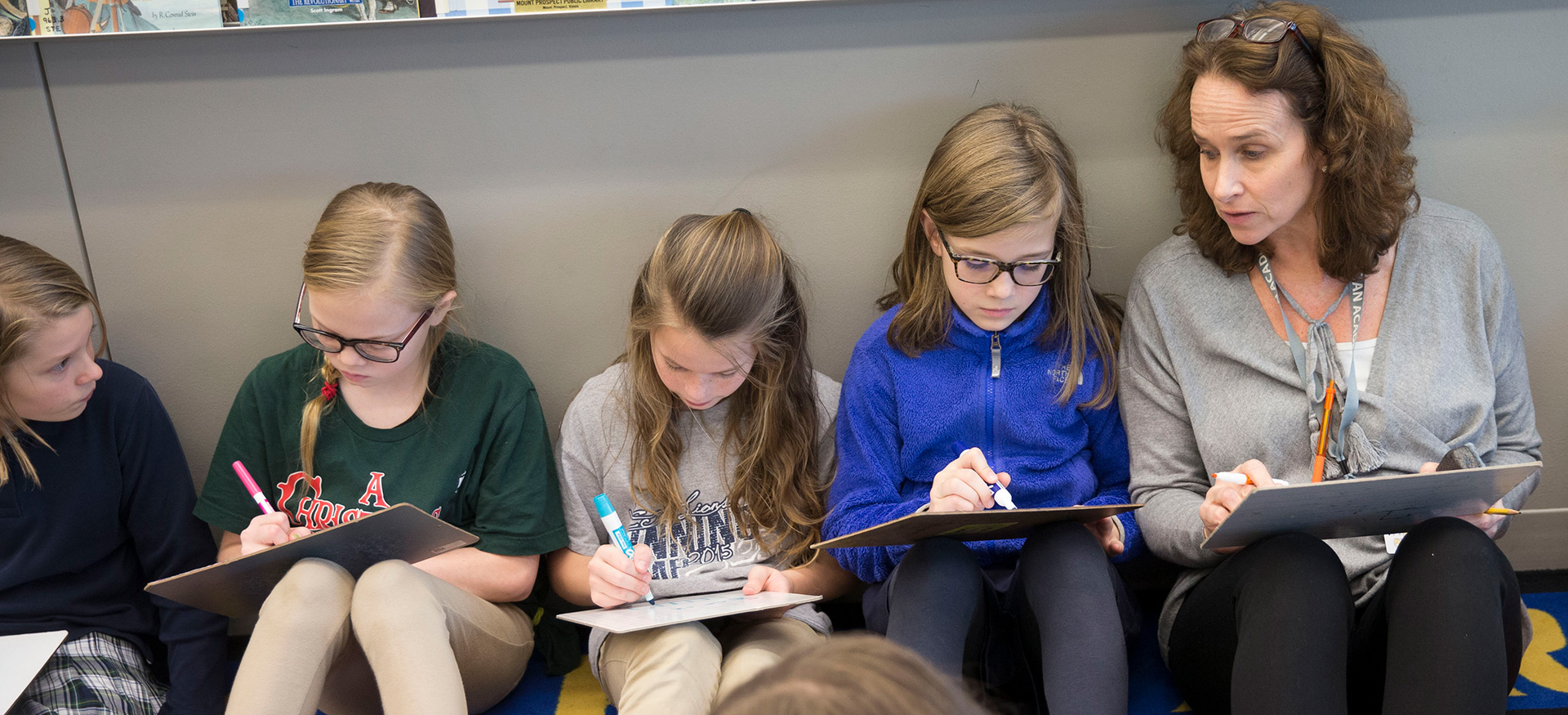 Teacher giving a lesson plan sitting on the floor with a group of students.