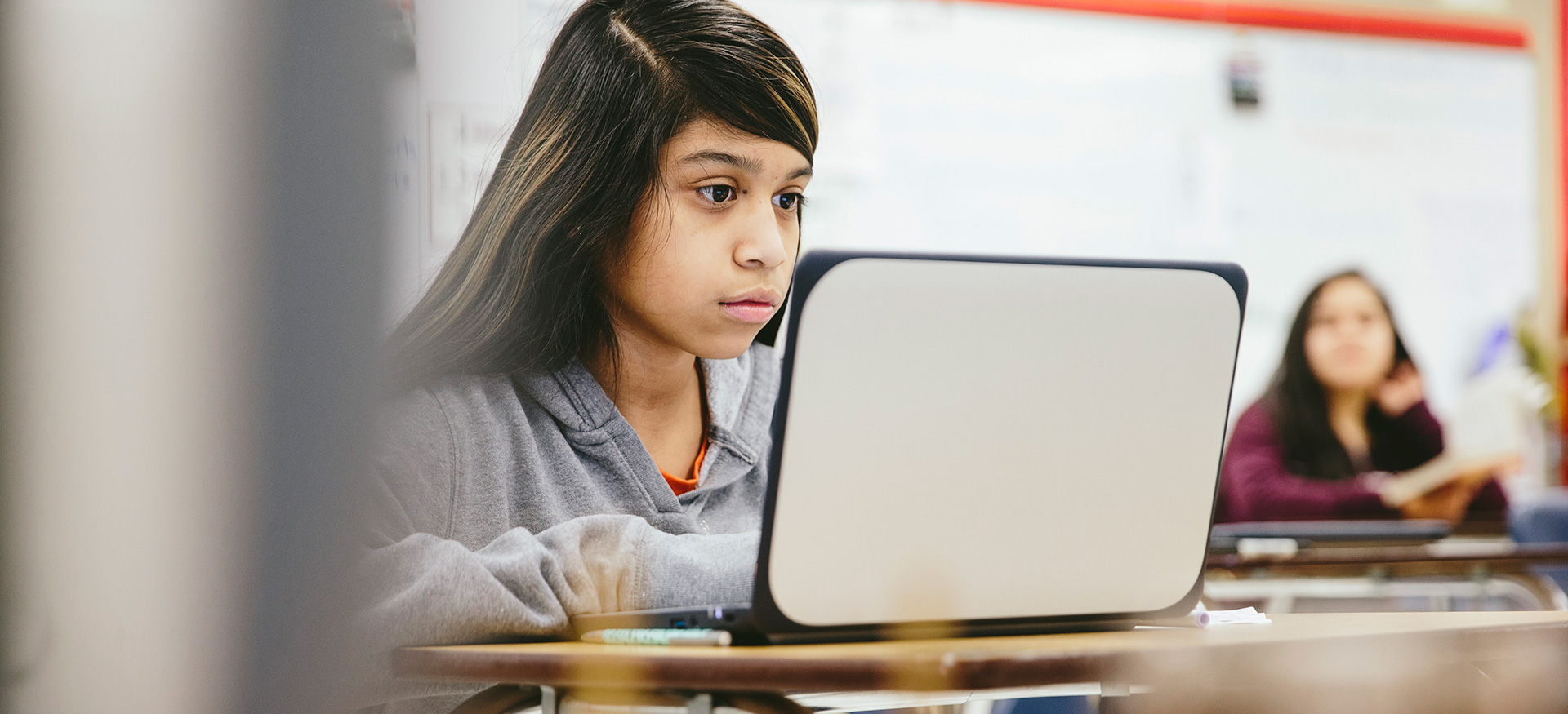 Student in a classroom working on a laptop.