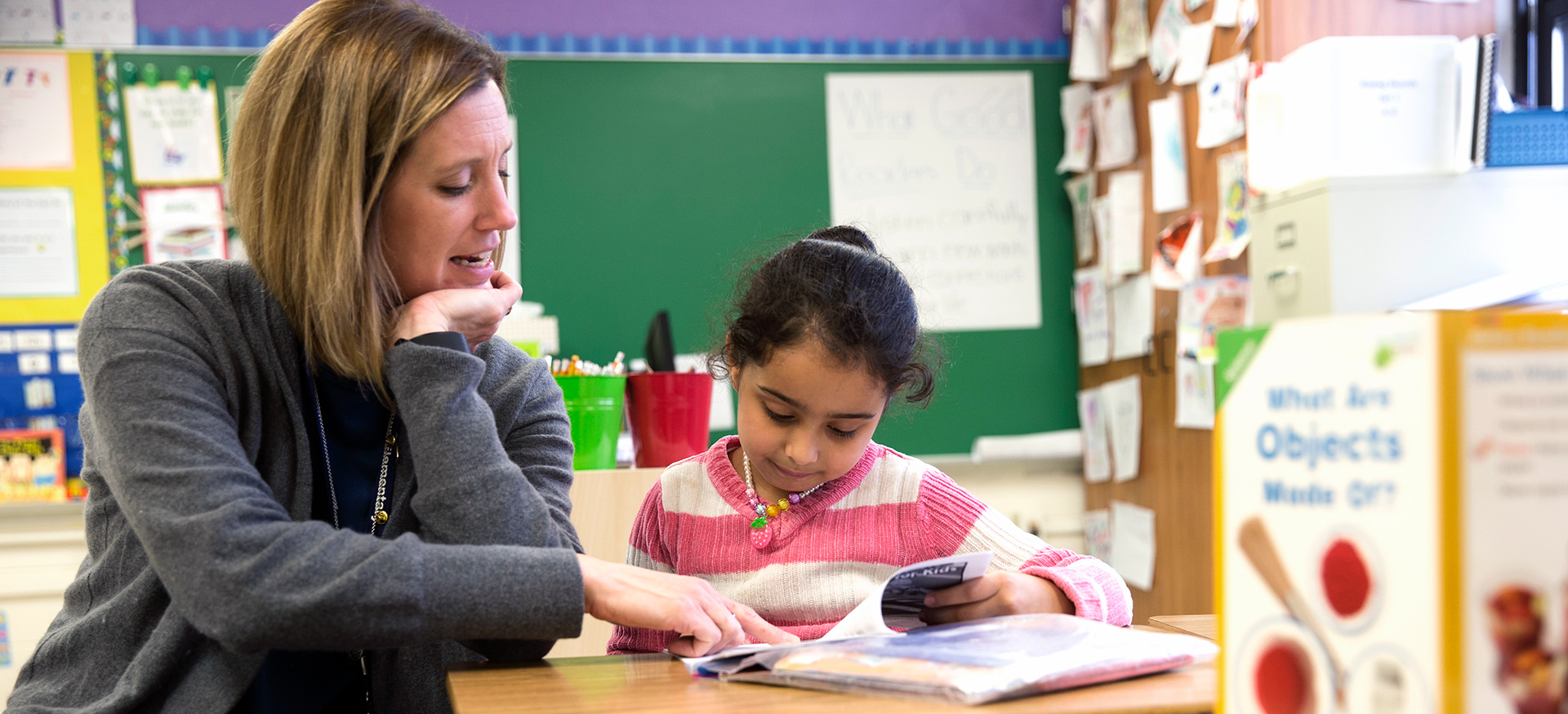 Teacher helping a young student with reading.